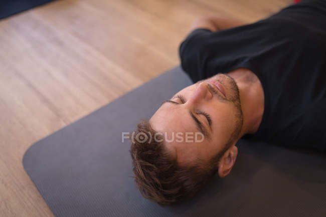 Молодой человек медитирует в фитнес-клубе — стоковое фото