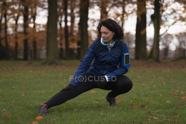 Young woman performing stretching exercise in the park — Stock Photo