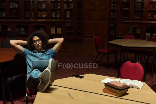 Молодой человек использует ноутбук в библиотеке — стоковое фото