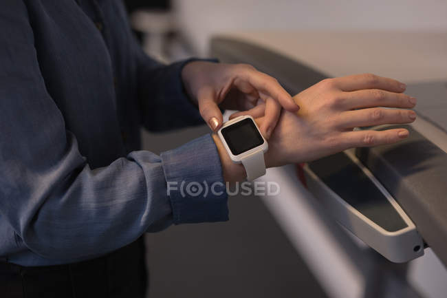 Mid section of female executive using smartwatch on treadmill in office — Stock Photo