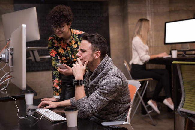 Executivo masculino e feminino discutindo sobre computador no escritório — Fotografia de Stock