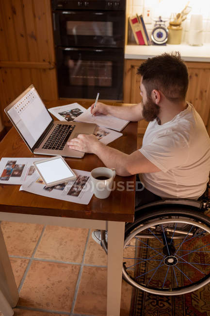Disabled man noting while using laptop at home — Stock Photo