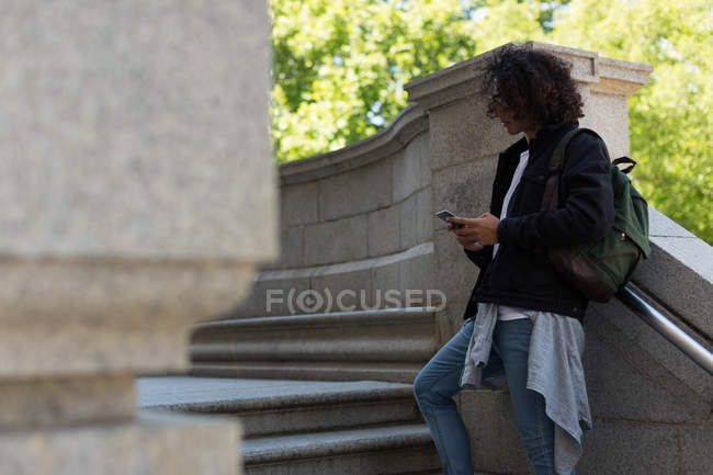 Giovane utilizzando il telefono cellulare al di fuori dell'edificio della biblioteca — Foto stock