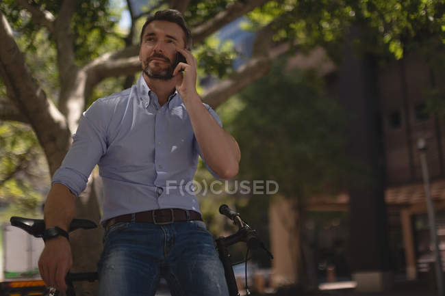 Homem falando no telefone celular perto da rua em um dia ensolarado — Fotografia de Stock