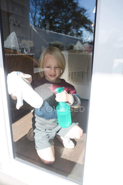 Boy cleaning window with rag cloth at home — Stock Photo