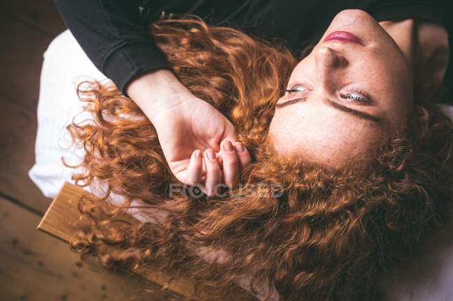 Thoughtful woman lying on bed in bedroom at home — Stock Photo
