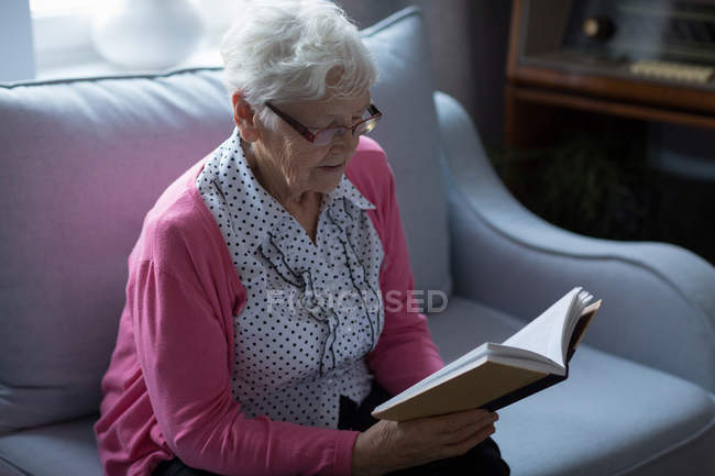 Seniorin liest zu Hause ein Buch — Stockfoto