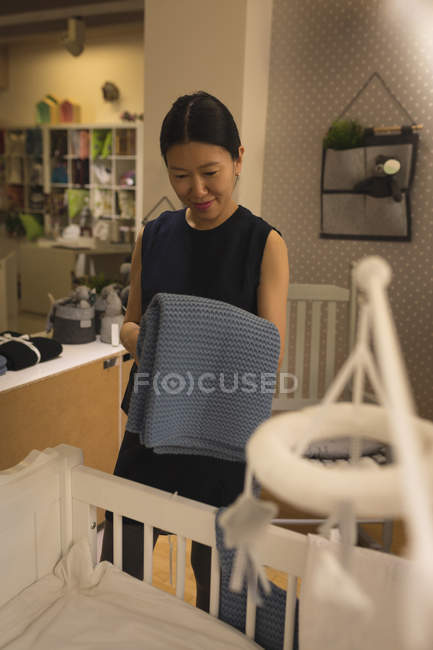 Happy pregnant woman looking at wooden cradle in store — Stock Photo