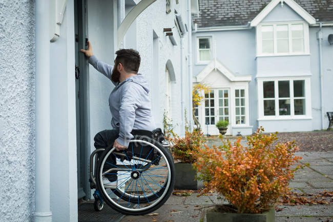 Людина з обмеженими можливостями дзвонить до дверей свого будинку — стокове фото