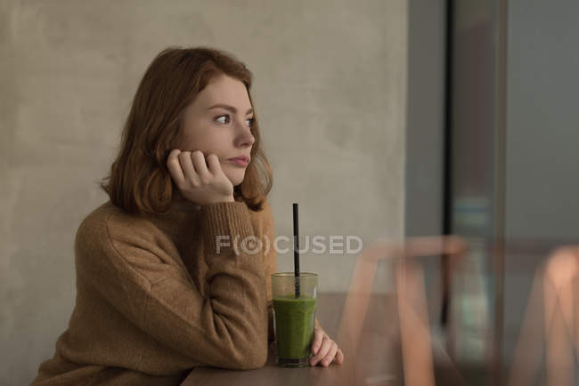 Удумлива жінка, що має здоров'я, трясе напій в кафе — стокове фото
