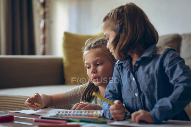 Siblings studying together in living room at home — Stock Photo