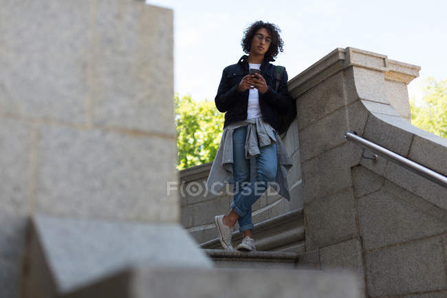 Young man using mobile phone outside library building — Stock Photo