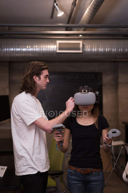 Чоловіча виконавча допомога жінці-виконавцю у використанні гарнітури віртуальної реальності в офісі — стокове фото