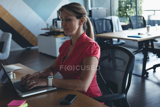 Empresária trabalhando no laptop na mesa no escritório — Fotografia de Stock