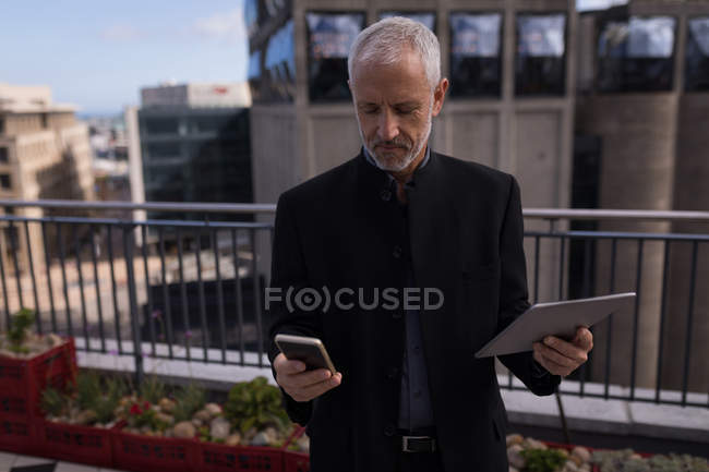 Бизнесмен, использующий мобильный телефон и цифровой планшет в помещениях отеля — стоковое фото
