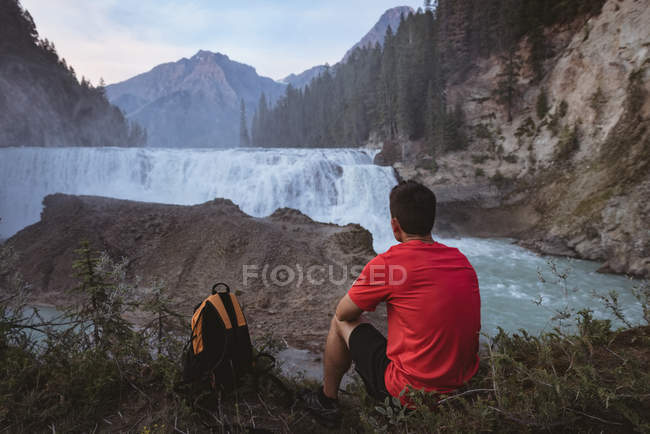 Vista trasera del hombre mirando la cascada - foto de stock