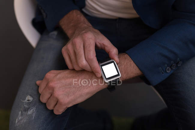 Imagen recortada de hombre de negocios usando smartwatch en la oficina - foto de stock