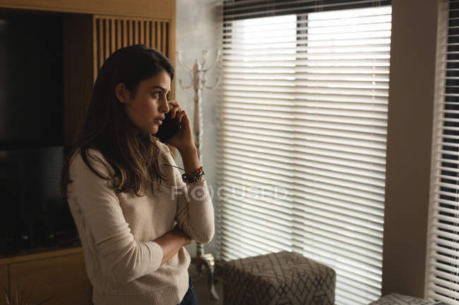 Женщина разговаривает по мобильному телефону дома — стоковое фото
