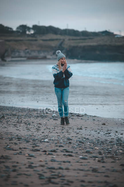 Mulher andando em uma praia ao entardecer — Fotografia de Stock