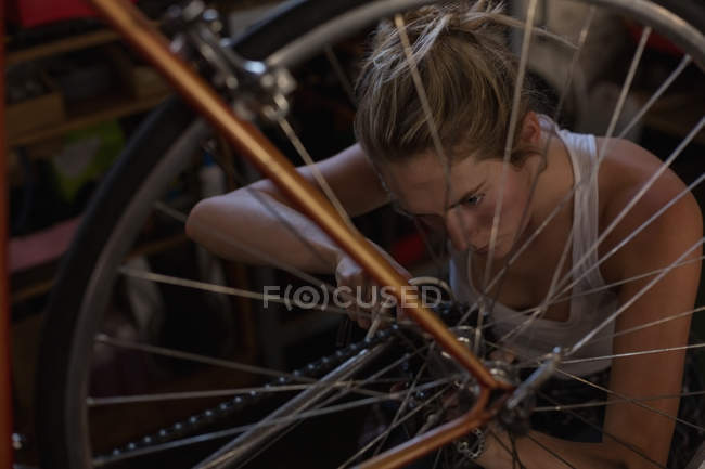 Junge Mechanikerin repariert Fahrrad in Werkstatt — Stockfoto