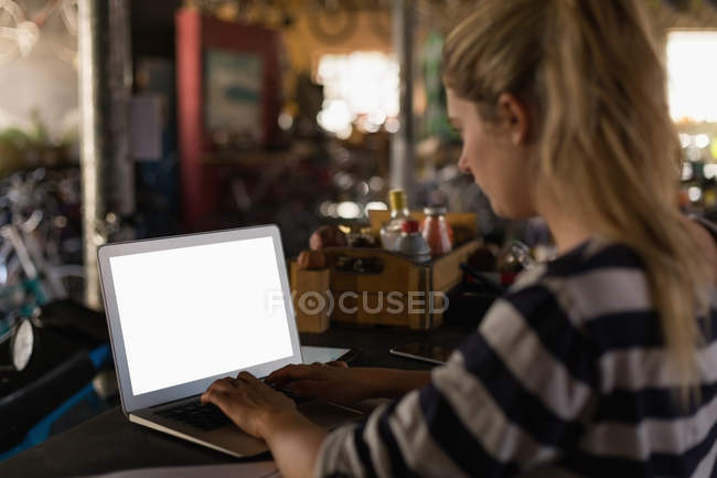 Молода механічна жінка використовує ноутбук у майстерні — стокове фото