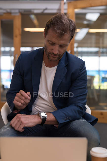 Бизнесмен использует умные часы в современном офисе — стоковое фото