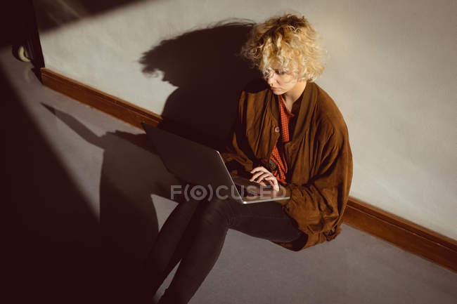 Young woman using laptop sitting on the floor — Stock Photo