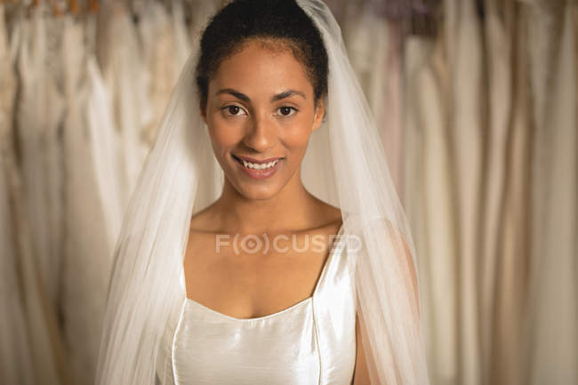Чувственная невеста смешанной расы в свадебном платье и вуаль, смотрящая в камеру — стоковое фото