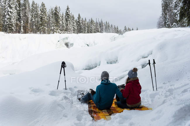 Пара сидять разом на сніжний пейзаж у зимовий період — стокове фото