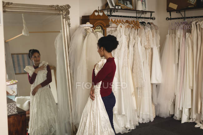 Young bride with white dress looking into mirror at boutique — Stock Photo