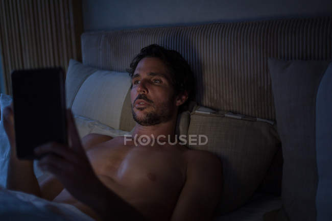 Mann nutzt digitales Tablet zu Hause im Schlafzimmer — Stockfoto