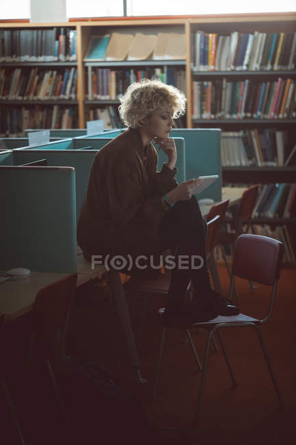 Jovem mulher usando tablet digital na biblioteca — Fotografia de Stock
