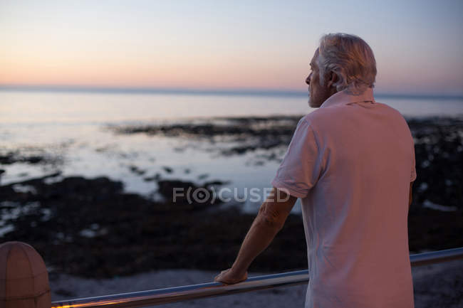 Nachdenklicher Senior steht in der Abenddämmerung in Strandnähe — Stockfoto