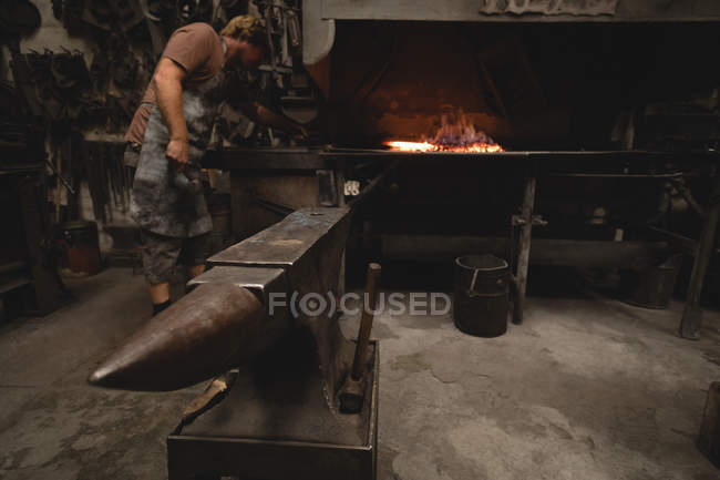 Ковальський нагрівальний металевий стрижень у вогні на майстерні — стокове фото