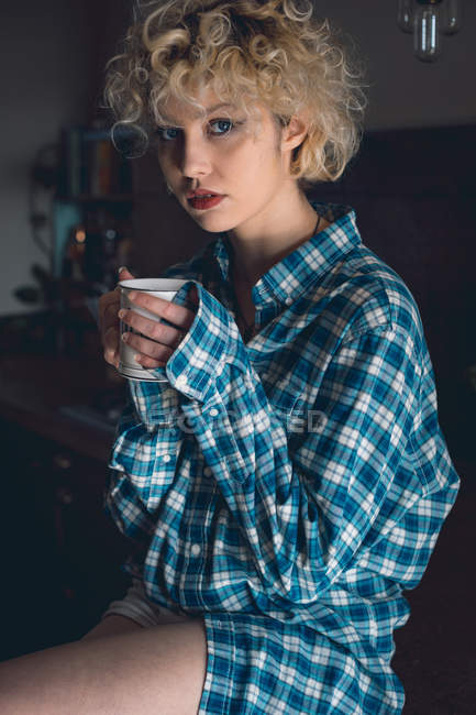 Молода жінка має каву на кухні вдома — стокове фото