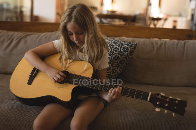 Menina tocando guitarra acústica na sala de estar em casa — Fotografia de Stock