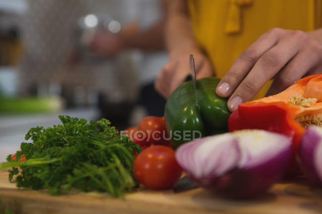Sezione media della donna che taglia le verdure in cucina a casa — Foto stock