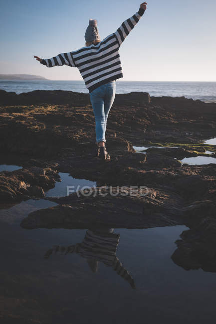 Mulher caminhando com os braços estendidos na praia em um dia ensolarado — Fotografia de Stock