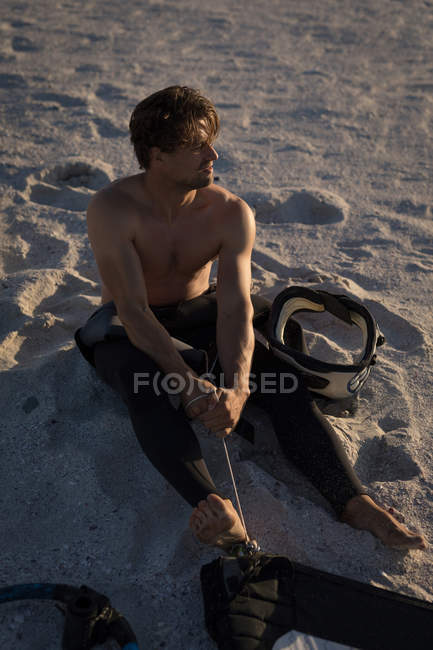 Hombre surfista preparando una cometa en una playa al atardecer - foto de stock