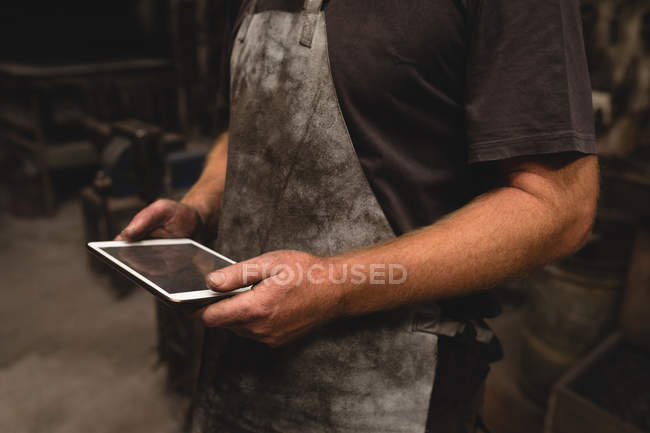 Mid section of blacksmith using digital tablet in workshop — Stock Photo