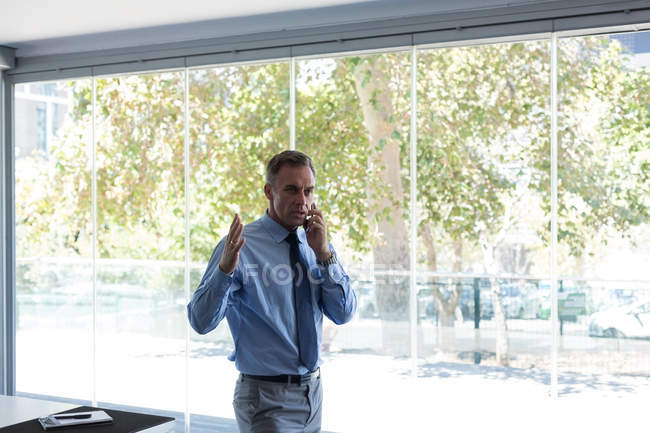 Hombre de negocios hablando por teléfono móvil en la oficina - foto de stock