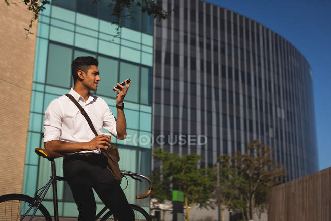Бизнесмен разговаривает по мобильному телефону за пределами офиса в солнечный день — стоковое фото