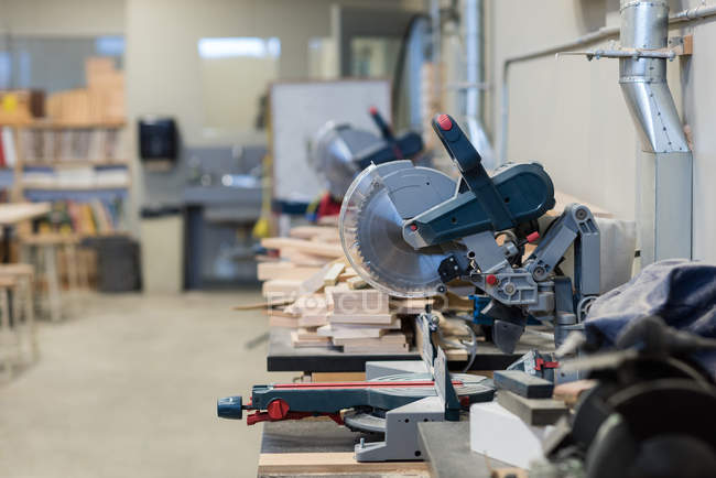 Máquina de corte de amoladora y piezas de madera en taller - foto de stock