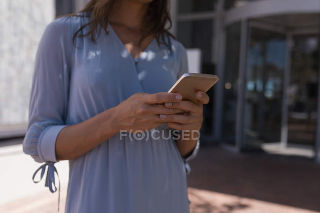 Sección media de la mujer que utiliza el teléfono móvil al aire libre - foto de stock