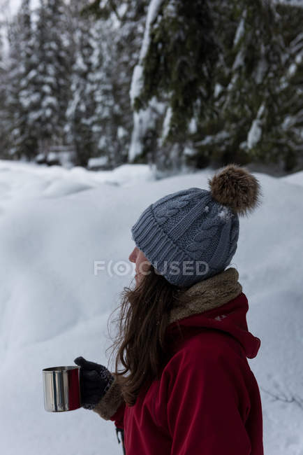 Жінка має каву на сніжному пейзажі взимку — стокове фото