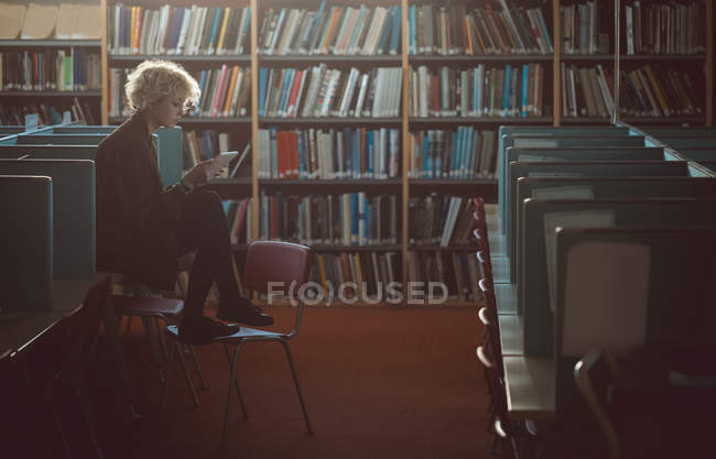 Jeune femme utilisant une tablette numérique dans la bibliothèque — Photo de stock