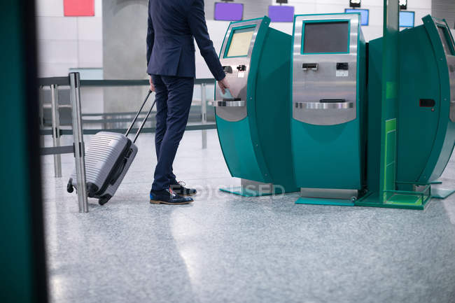 Empresário usando a máquina de bilhetes de avião no aeroporto — Fotografia de Stock