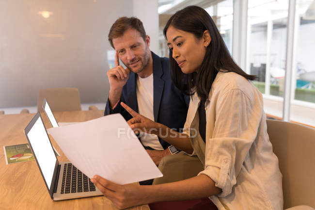 Compañeros de negocios discutiendo sobre documentos en la sala de conferencias en la oficina - foto de stock