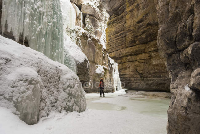 Mulher alpinista olhando para montanha de gelo rochoso durante o inverno — Fotografia de Stock