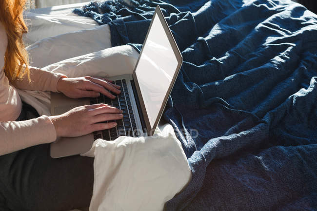 Частковий вид жінки, що використовує ноутбук у спальні вдома — стокове фото